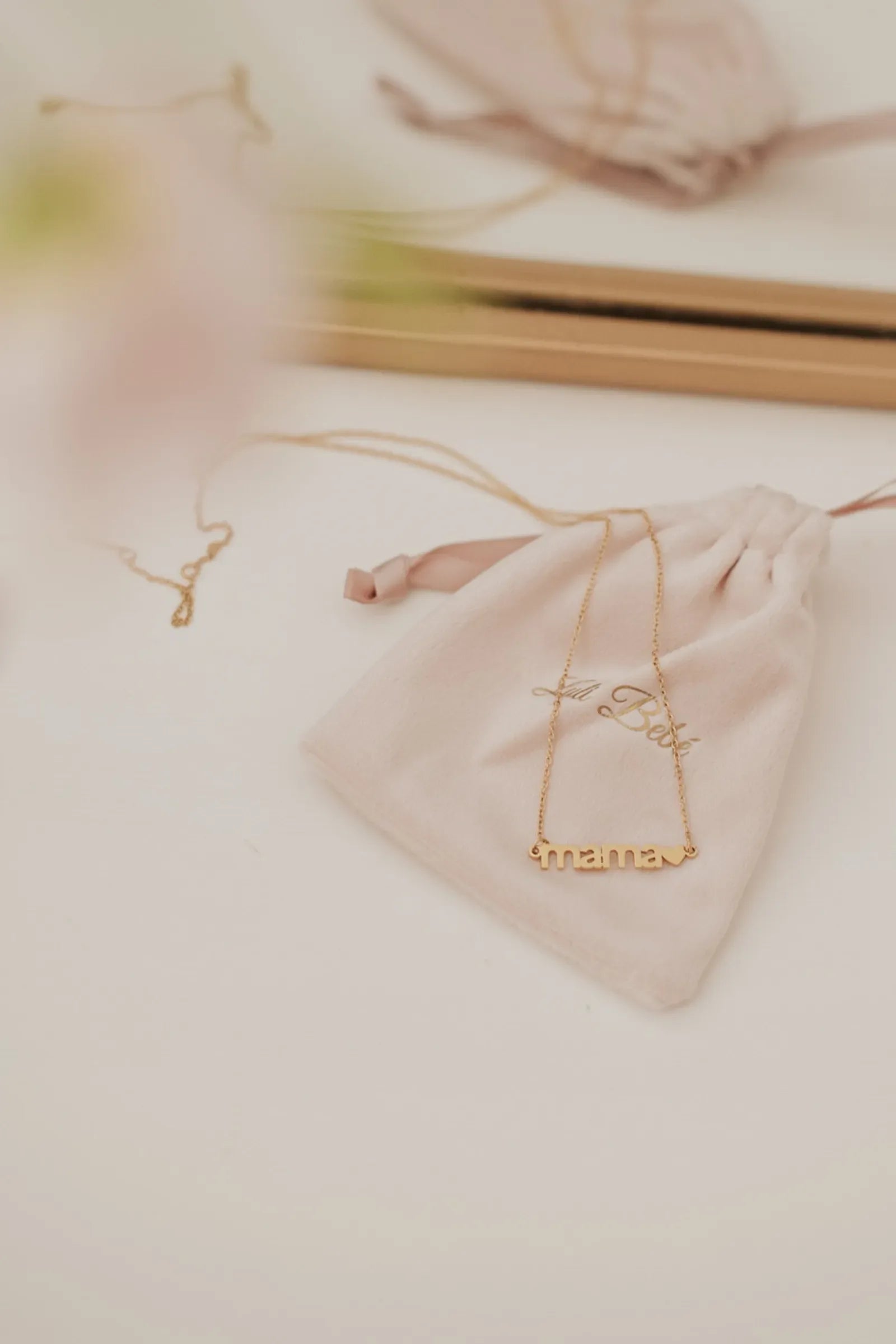 Gold mama necklace on soft pink Luli Bebé pouch with drawstring