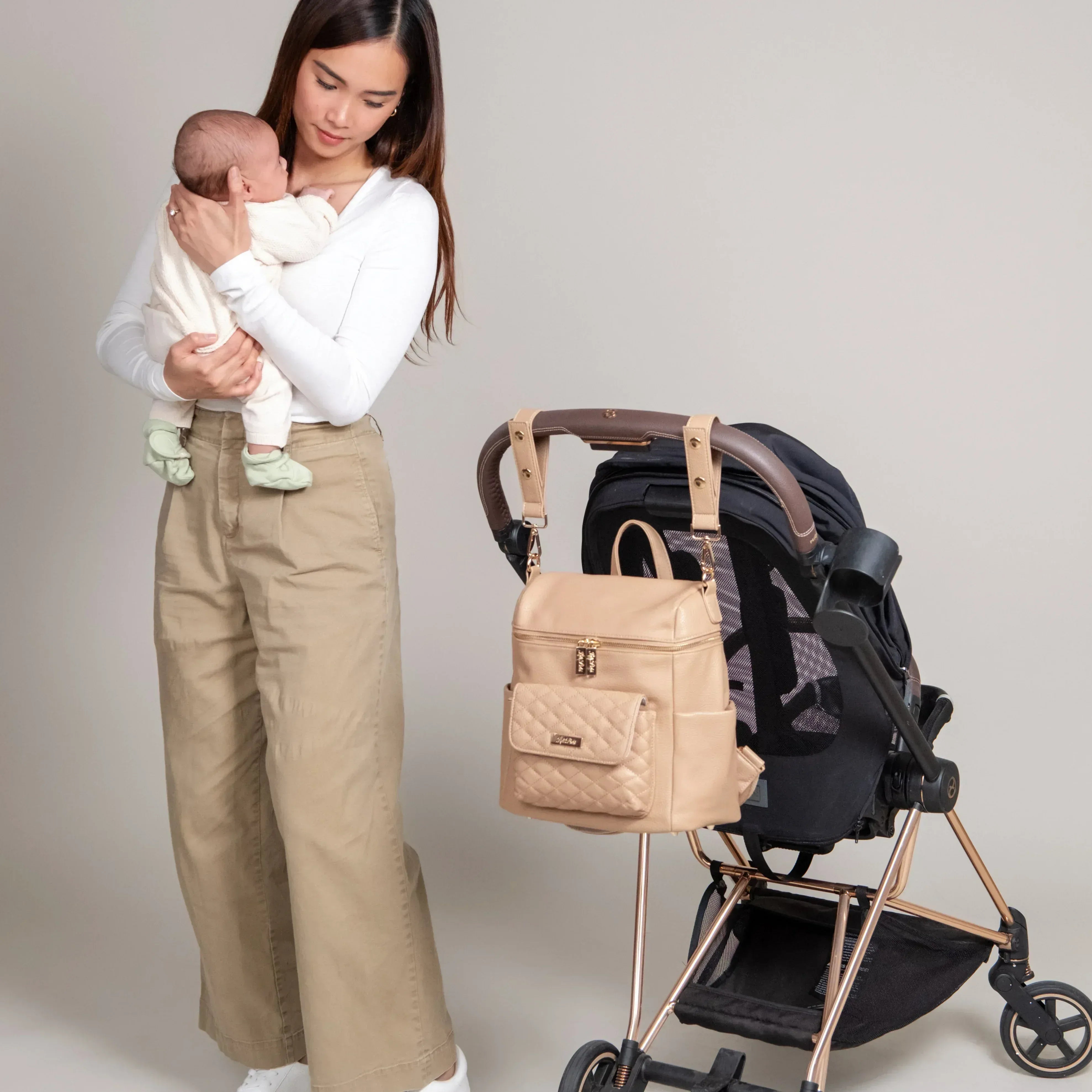 Latte Diaper Bag –Baby changing bag by Luli Bebe, lifestyle photo of mom with baby and stroller using stylish mini diaper bag backpack