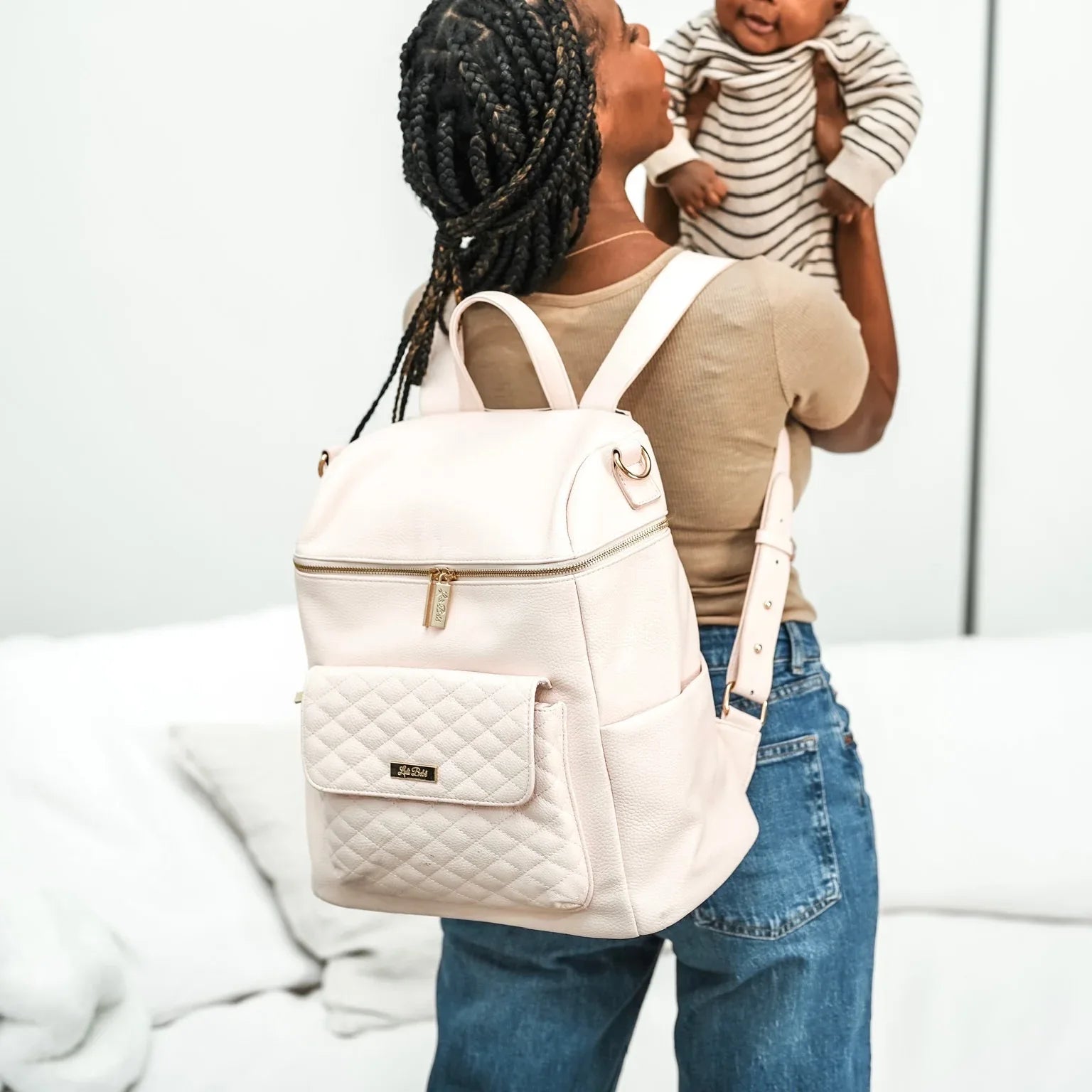 Pink diaper bag backpack worn by mom holding baby – Monaco collection by Luli Bebe, stylish vegan leather and practical hands-free design
