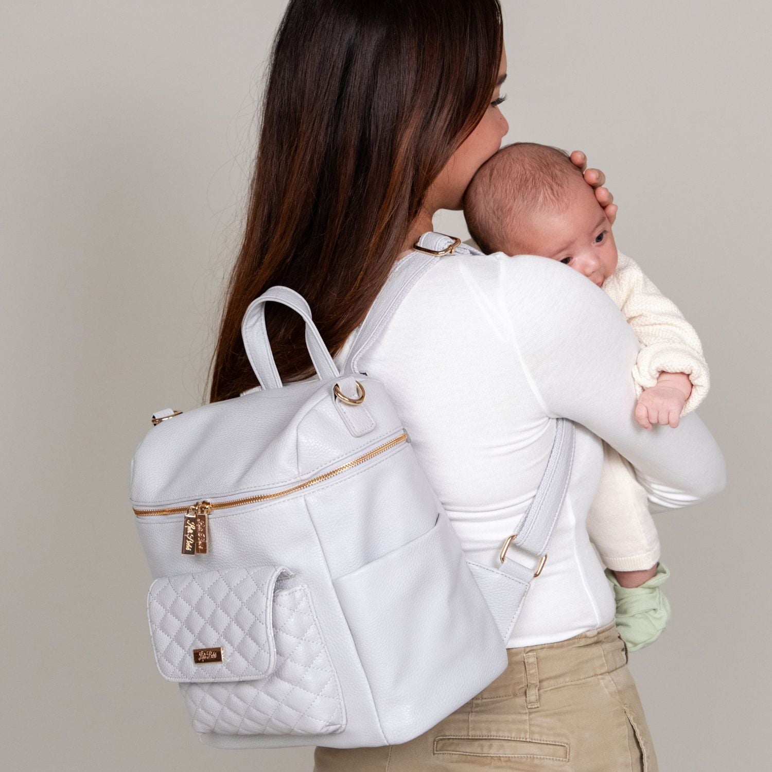 Stylish mother with baby, carrying a mini designer diaper backpack