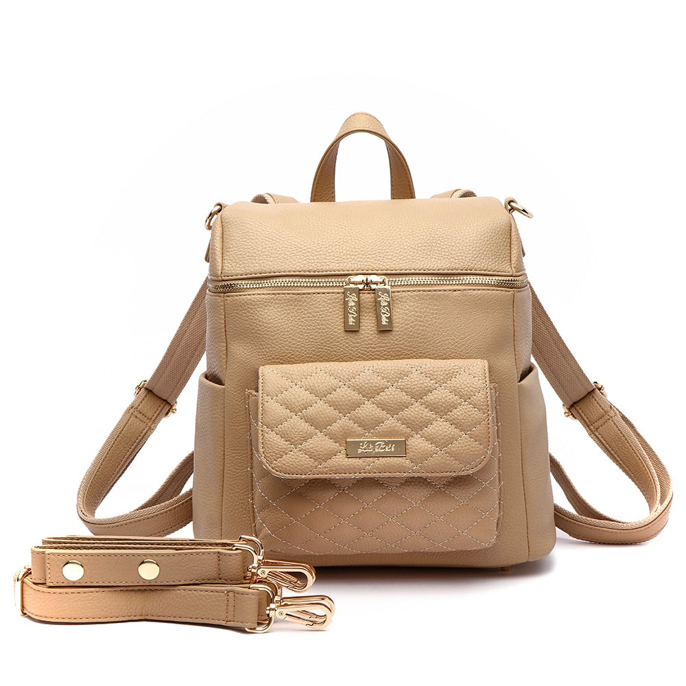 A latte-colored Petit Monaco diaper bag made from vegan leather, featuring a compact design with multiple pockets and a quilted pattern on the front.